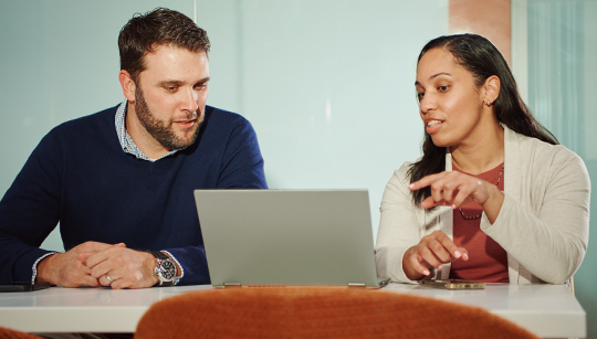 Two employees working on a laptop