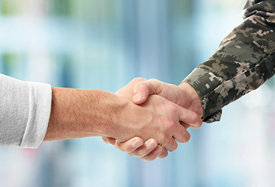 Photo of a handshake - one arm is wearing military camouflage