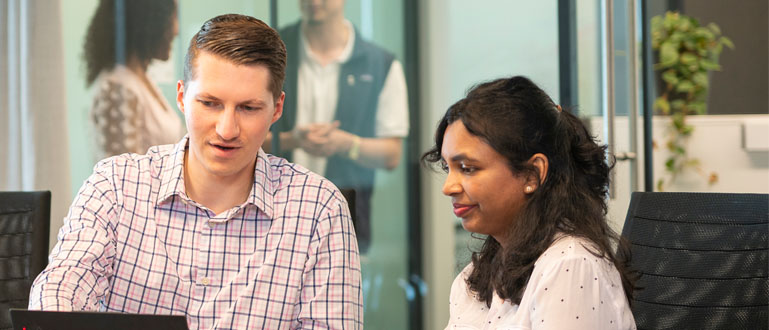 Photo of two people looking at a laptop
